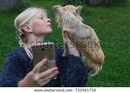 teen girl taking pictures on a mobile phone for himself and his beloved dog/beautiful teen girl with mobile phone in hand and a Chihuahua closeup in summer Park