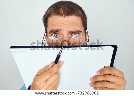 business man in glasses shows a pen on a white sheet of paper on a light background portrait                               