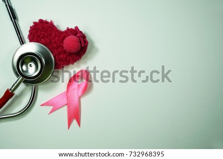 Health care and Medicine Concept - A Stethoscope, pink ribbon and a pink heart shape on a book over a white background. Breast cancer awareness pink sign symbol for help illness people