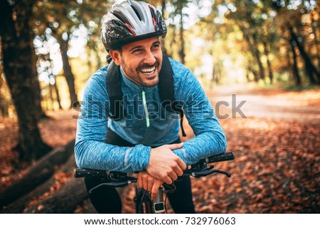 Happy male cyclist in forest. Royalty-Free Stock Photo #732976063