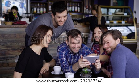 Attractive guys and girls in the cafe, do selfie on the phone. A company of friends is photographed together for social networks. 