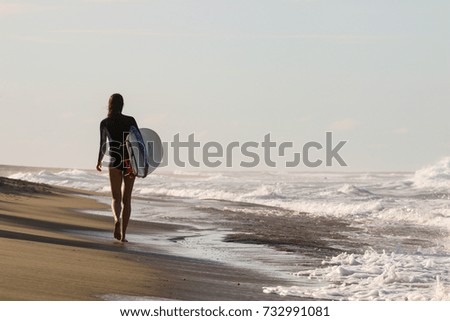Young surfer girl walking on the beach, Dominican Republic