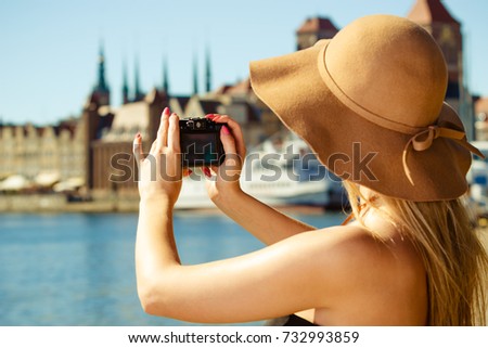Tourism, artistic, elegant fashion. Woman in elegant outfit and sun hat taking pictures.