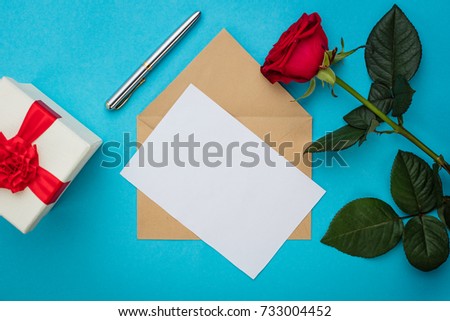 Romantic background of blank paper, pen, red rose and gift wrap with red bow. Copy space, top view