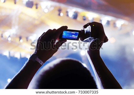 Video recording of the concert on the camera of the rock band party. Blue conceptual background of the youth party.