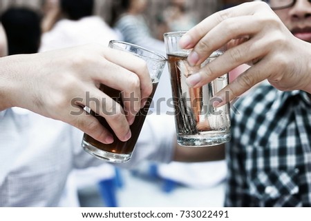 Happy time of two people hands clink glasses in party. Dramatic toned image.