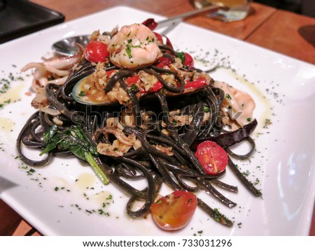 Seafood Squid Ink Fettuccine with chili sauce serve on white plate. 