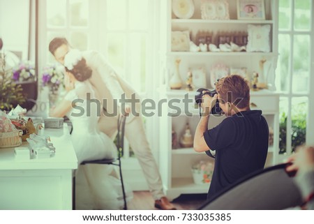 wedding photographer in action. Photography taking photographs of groom and bride vintage tone with sunlight effect picture Behind the scenes concept.