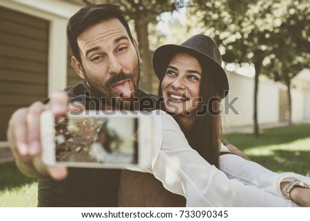 Young happy couple take a funny Self Portrait in city park. 