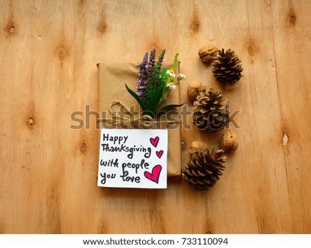 A rustic gift in paper craft with Happy Thanksgiving with people you love text on a note on wooden table