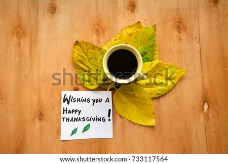 Autumn leaves with coffee cup and wishing you a Happy Thanksgiving text on a note on wooden table
