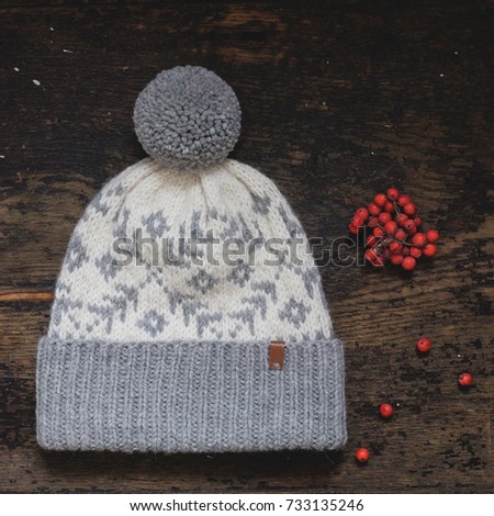 Gray knitted hat with a pompon on a wooden background