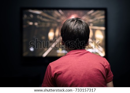 Facing back caucasian little boy watching television. Television and video game addiction. Royalty-Free Stock Photo #733157317