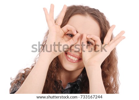 Portrait of a funny young girl looking at camera through fingers isolated on a white background