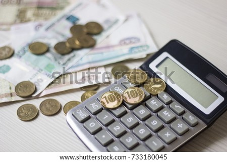 Money concept. Green calculator with coins and notebook on wooden table