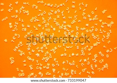 Top view of pasta. Raw spilled Italian pasta view from above on orange background alphabet Royalty-Free Stock Photo #733199047