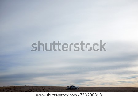 A four wheel drive car in a vast, barren desert landscape under a stormy, overcast sky. Royalty-Free Stock Photo #733200313