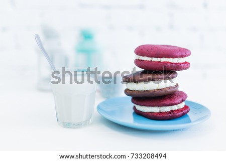 Image of three whoopie pies or moon pies with glass of milk and spoon.