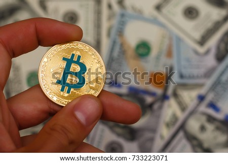 Golden bitcoin coin on man s hand on blurred us dollar bills background copy space