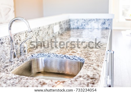 New modern faucet and kitchen sink closeup with granite countertops Royalty-Free Stock Photo #733234054