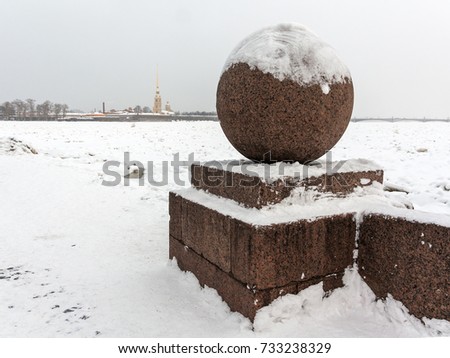Landmark in Saint Petersburg, Russia: the Spit of Vasilievsky Island  by a winter day with granite sphere, Peter and Paul fortress and dom at the horizon and the Neva river covered by snow and ice.