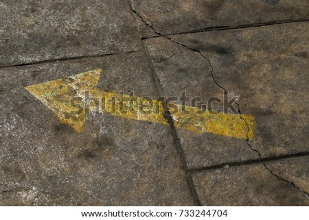 Yellow arrow painted onto a path showing the direction