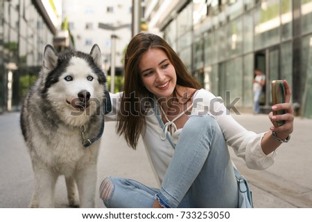 Teenage girl with dog in city making self portrait. 