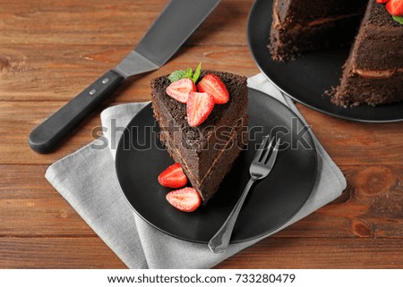 Plate with piece of delicious chocolate cake on table
