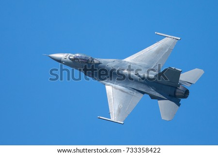 F-16 Fighting Falcon in a high-G maneuver, with condensation streaks around the plane. Royalty-Free Stock Photo #733358422