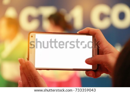 Blur of woman hands take photo or recording speaker with smart phone, camcorder mobile operator working for record speaker on stage in conference and convention hall  blank white screen on recording