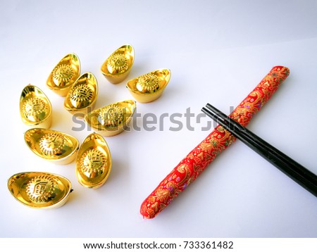 chinese gold ingots with Chinese characters word (yuan bao), a symbol of wealth for Chinese and chopsticks with the red cover on isolated background