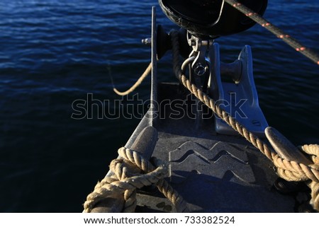 View from the bow of a sailboat at anchor with beautiful blue water in the background.