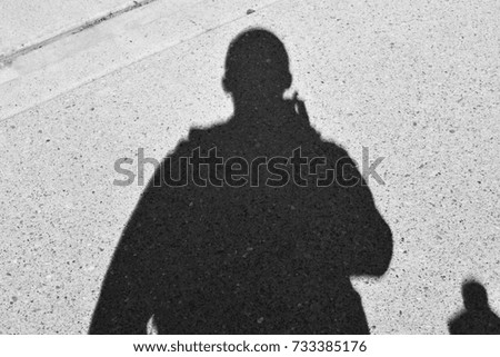 Silhouette of man standing over asphalt driveway