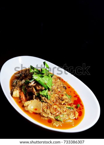 The picture of stir fried seafood with curry powder in white dish on black background.