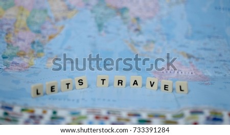 Wording of "LETS TRAVEL" with world map background.
