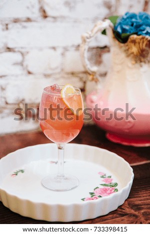 Pink alcoholic cocktail in a tall wine glass next to vintage tableware