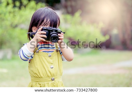 Little Asian girl is taking a photo.