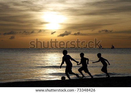 Silhouette of young boys playing at the beach during sunset Royalty-Free Stock Photo #73348426