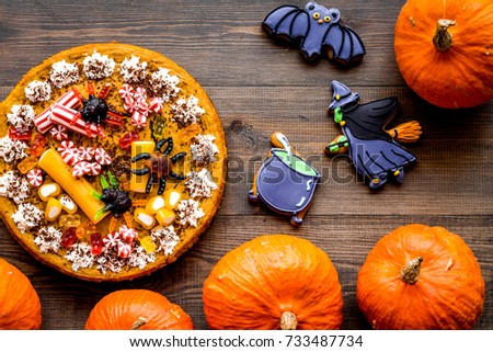 Halloween bakery and sweets. Pumpkin pie, gummy spiders, gingerbread cookies on wooden background top view