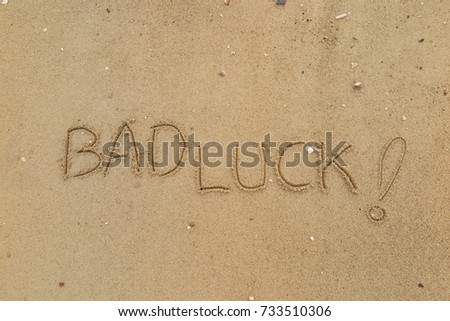 Handwriting  words "BAD LUCK!" on sand of beach.