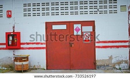 Red door on cement wall of chemical storage room