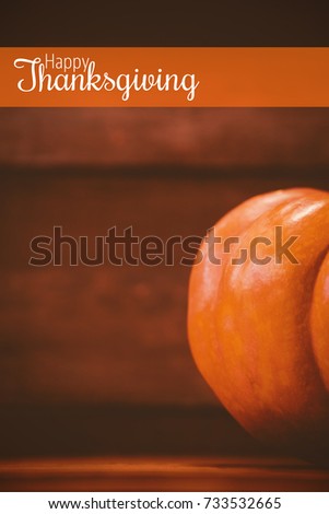 Thanksgiving greeting text against cropped image of pumpkin on table during halloween