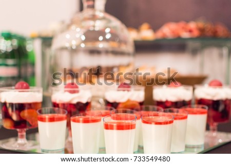 Desserts with fruits, mousse, biscuits. A grouping of desserts from strawberry cheesecake to powdered donuts. Festive culinary sweet masterpieces. Blurred abstract picture. Delicious Desserts. 