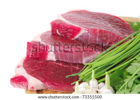 fresh meat : raw uncooked fat lamb pork fillet with green stuff and garlic on wooden plate isolated over white background