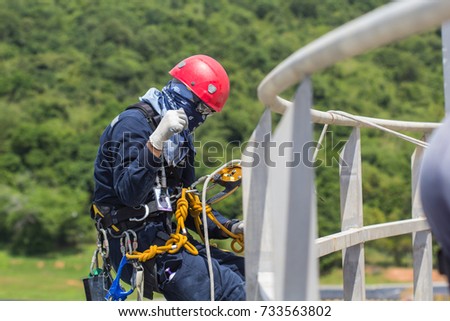 Focus  male worker rope access height handrail inspection of thickness storage propane  tank industry background  forest mountain