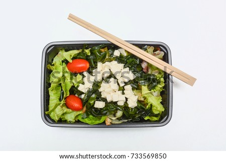 Japanese style fast food (bento), Salad box, Green fresh organic vegetables mixed 
Lettuce, tofu, Seaweed and red tomatoes with wood chopstick in plastic box on work table, easy to eat or delivery.