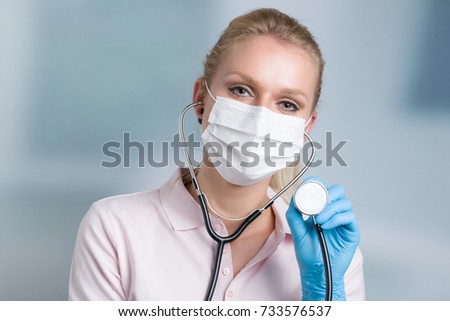 nurse with a stethoscope and medical face mask in front of a clinic room