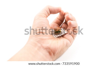 Hand holding mini burger. Concept of small portion. Isolated on white background. Slightly de-focused and close-up shot. Copy space.