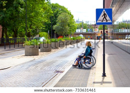 adult woman on wheelchair crossing the street in the city