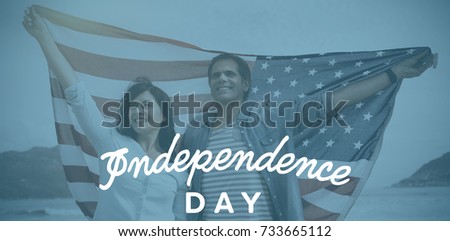 Independence day text against white background against mature couple holding american flag at beach